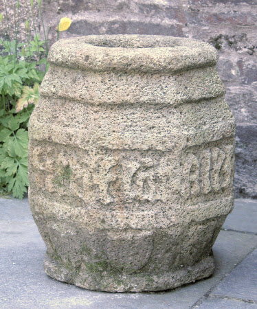 Cresset stone, of barrel shape in octagonal form; carved with inscription and decorative icons.