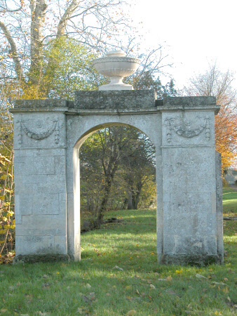 Arch decorated with swags and surmounted by elliptical Coade stone punchbowl urn 