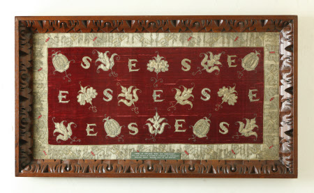 Long cushion of crimson velvet with applied floral motifs and the initials 'E S'