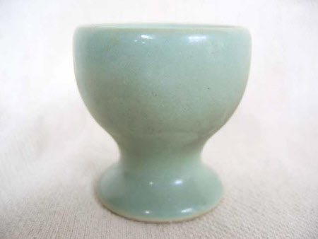 Seven pale green earthenware egg cups.