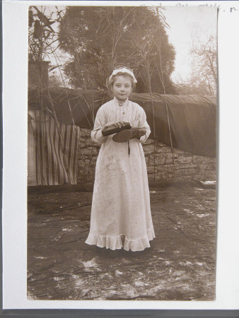Unknown Village schoolgirl dressed in costumes of a servant cleaning a shoe, Dyrham School, ...