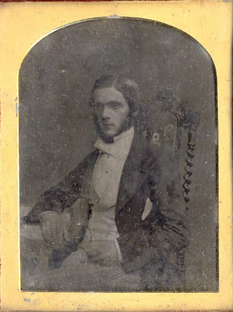 Gentleman seated with his right arm on a table