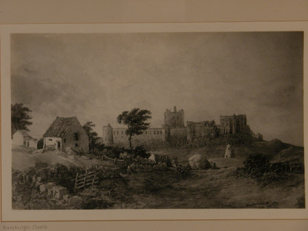 View of Bamburgh Castle from inland with stone walls, a haystack and a little barn in the foreground