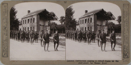 London Territorials passing a ruined house on the shell-swept La Bassee Road