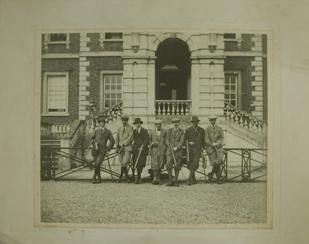 A shooting party carrying guns leaning against metal railings in front of Wimpole Hall. The Hon. ...