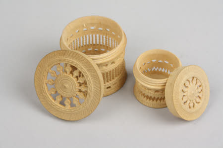 A set of two carved fretwork circular wooden ornamental boxes with screwtop lids.