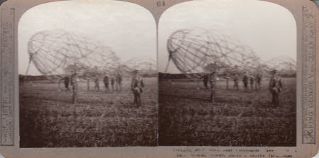 Zeppelling shot down near Colchester even with its back broken, towers above a nearby farm house.
