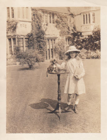 Elizabeth Hussey as a young girl standing outside with a small dog on a table