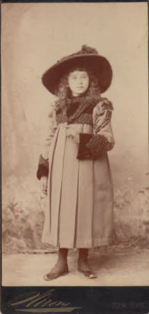 Portrait of a young girl standing against an outdoors background, wearing winter clothes.  Possibly ...
