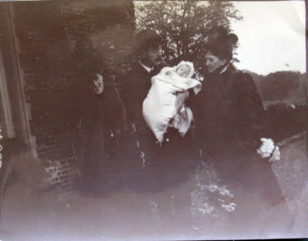 Henry Edward Sparke Upcher holding a baby in his arms with two ladies.