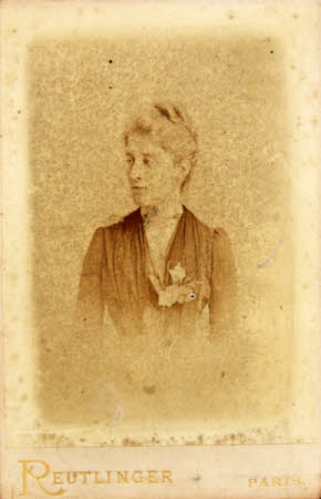 A half length portrait of a woman wearing a dark dress with corsage with her hair up.
