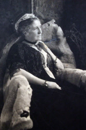 A lady seated in an armchair covered with a fur rug.
