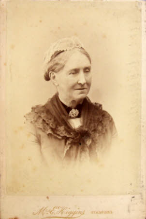 A woman, hair tied up with lace, wearing a black choker and brooch and dark lace around her ...
