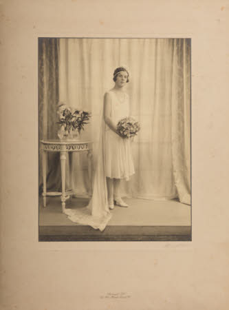 A full length portrait of a young woman in bride's dress.