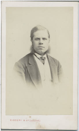 A half length portrait of a man with pronounced sideburns, dressed in a suit and cravat.