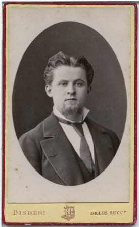 A portrait of a young bearded man in suit and tie.