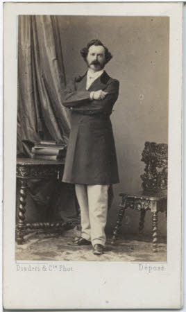 A portrait of a moustachioed man, arms crossed.