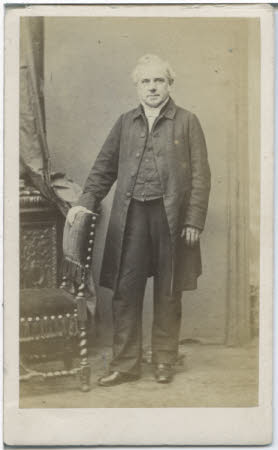 A portrait of of a white haired gentleman in long coat and waistcoat.