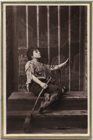 Portrait of an un-named woman sat on steps and holding a broom