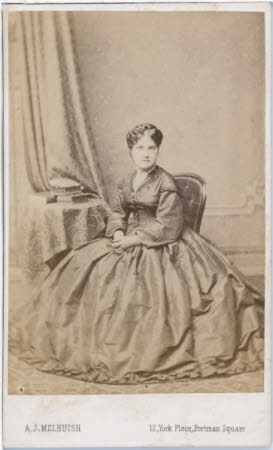 A full length portrait of a seated lady wearing a full dark dress