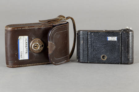 Icarette folding rollfilm camera with brown leather carrying case.