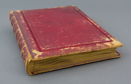 Red leather-bound photograph album containing prints