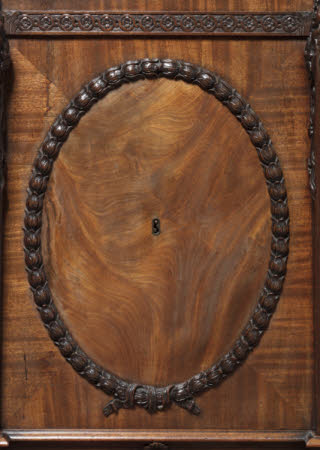 Detail of the applied oval of carved husks framing finely-figured veneers and a brass-lined keyhole to the door of one of the pedestals to the library table © National Trust Images / John Hammond