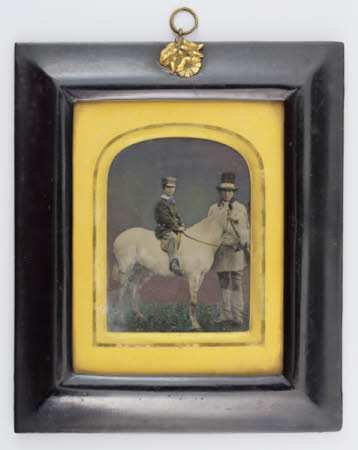 Portrait of a boy on a pony, with groom.